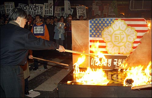 24일 저녁 국회앞에서 이라크 파병반대 촛불시위를 벌인 참가자들이 국회마크가 그려진 성조기를 불태우고 있다. 